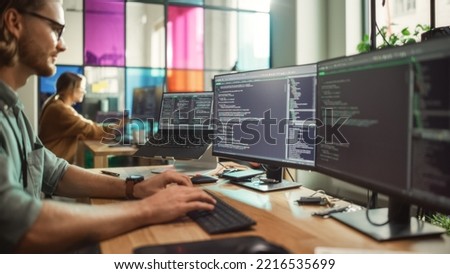 Male Programmer Coding on Desktop Computer With Two Monitors Set Up in Creative Office. Caucasian Man Using Artificial Intelligence to Create Innovative Software for Start-up Company. Foto d'archivio © 