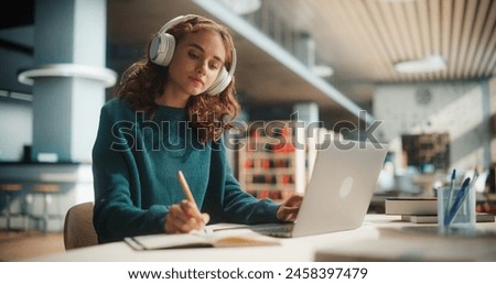 Similar – Image, Stock Photo Student learning in university library. Young woman having video class listening to online course using laptop. Focused student studying for college exams. Using technology