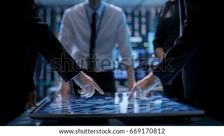 Corporate Managers Working at the Table in Monitoring Room. Room is Full of State of the Art Technology. Computers with Animated Screens. 商業照片 © 