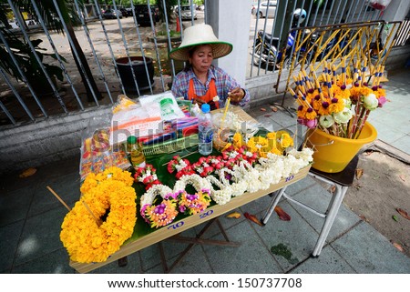 BANGKOK, THAILAND - AUGUST 17 : Unidentified woman to make flower garlands in Thai style for sell to worship at Bangkok city pillar shrine on August 17, 2013 in Bangkok, Thailand.
