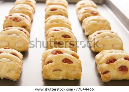 Strawberry strudel bites in rolls on a cookie sheet.