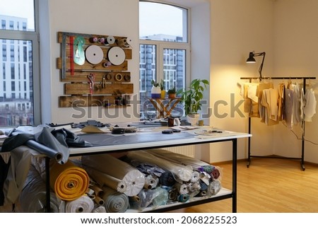 Fashion designer working studio interior with workplace table, fabric materials and sewing patterns for clothes designing, tailoring. Atelier workshop space. Small business and self employment concept Foto stock © 