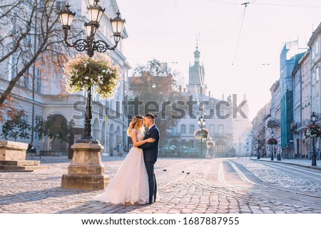 Image, Stock Photo Beautiful newlyweds hugging near the ancient door. Wedding portrait of a stylish groom and a young bride near old house in in a European town