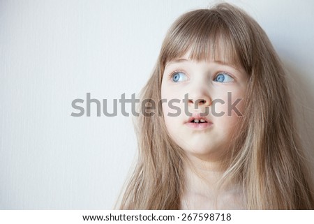 Portrait of a pretty little girl with opened eyes wide, neutral background
