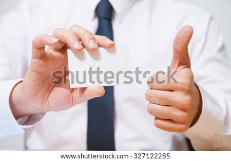 Businessman holding  a business card and showing a thumb up sign - closeup shot