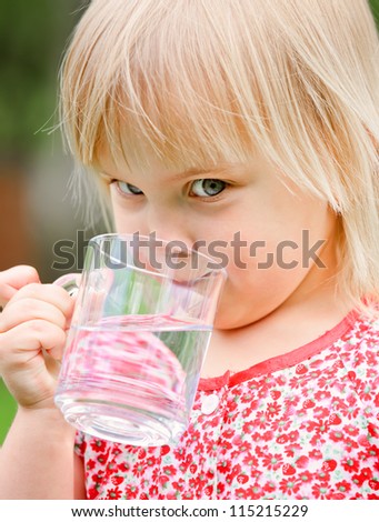 Cute little girl drinking water outdoors