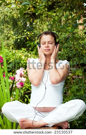 Young woman listening to a music at summer garden