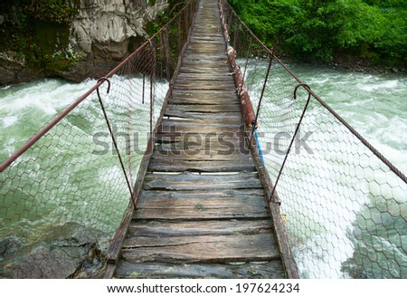 Rickety foot bridge over white water