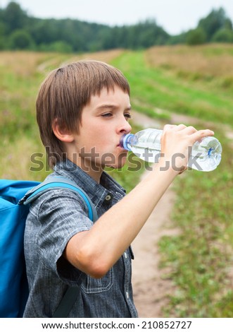Boy drinking water from pet bottle outdoors