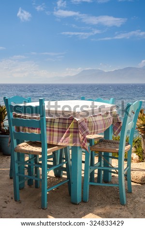 Blue wooden table with chairs of outdoor greek cafe overlooking the sea
