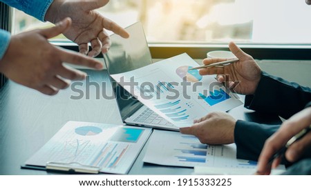 A businessman studying statistics and holding a graph document by hand An office worker stood near the desk with a laptop. Man pointing finger Foto stock © 