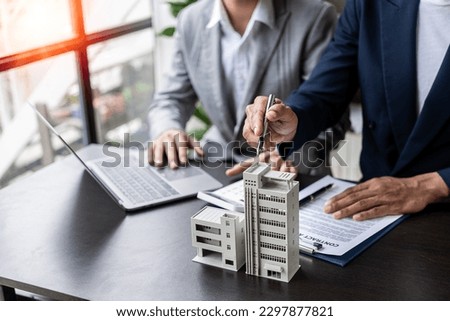 Real estate agents offer contracts to buy or rent housing. Businessman holding model small building house with property insurance at table in home sales office Imagine de stoc © 