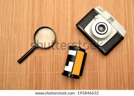 Old photo camera, roll of film and magnifying glass