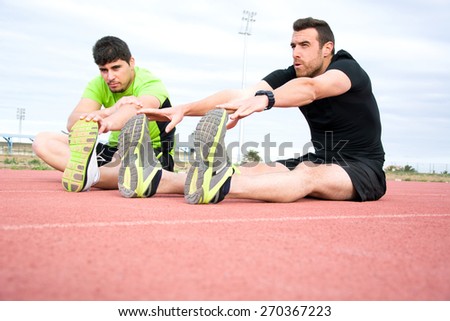two men stretching in running track