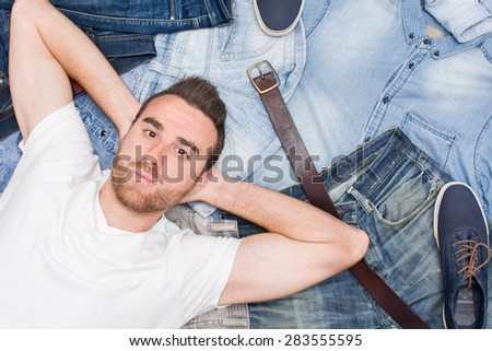 man lying on many jean clothes