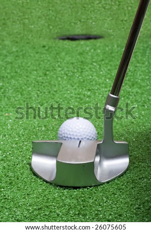 A putter lines up on the green to sink a golf ball.