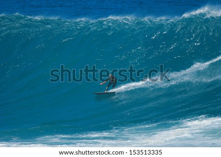 A surfer glides across the face of a huge wave.