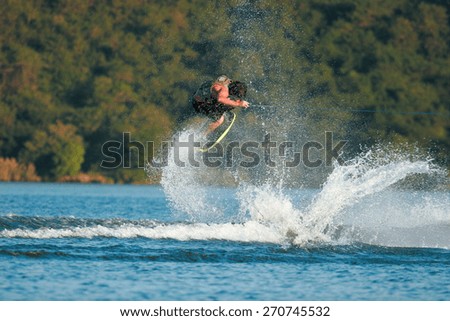 A wakeskater launches off the wake behind a boat.