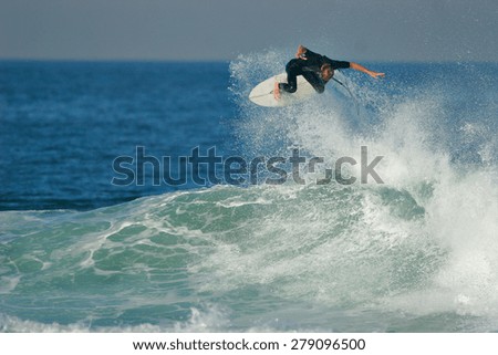 A surfer executes a radical aerial on a blue ocean wave.