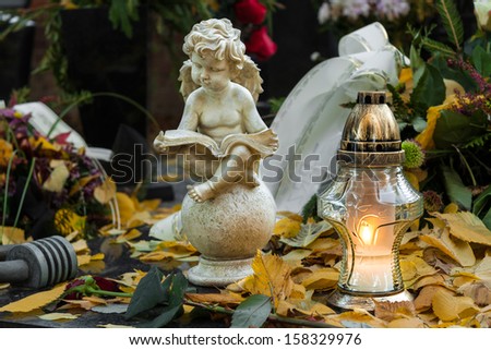 Votive candle and angel figurine on grave