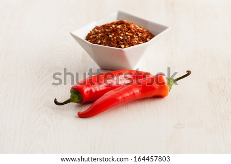 Red flaked chili pepper in white bowl and bean pods