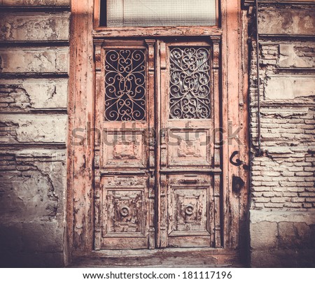 Old wooden door with ornament and brick wall in Old Tbilisi, Georgia. Toned in vintage colors