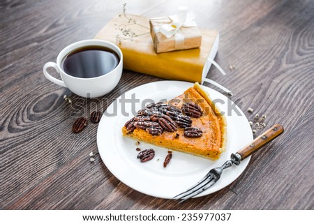 Pecan and pumpkin cake on plate with tea and books on wooden background
