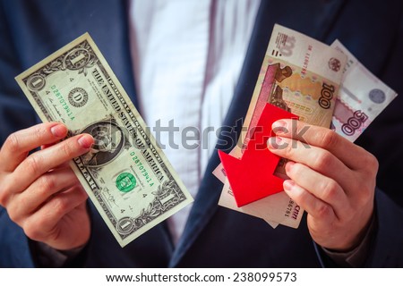 Business person holds roubles, dollars and red arrow. Devaluation of the Russian rouble.