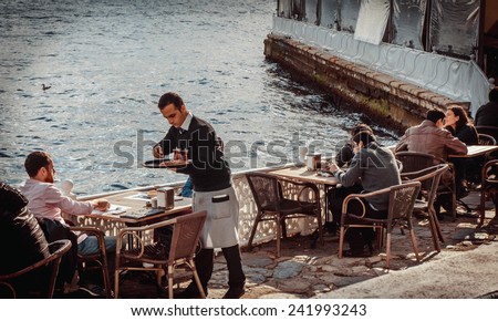 ISTANBUL, TURKEY- october 23, 2014: Waiter serves tea and some snack to a tourist in a street cafe on a coast of Bosphorus in Istanbul, Turkey. Toned image.