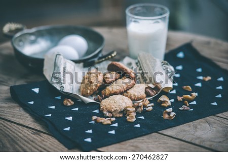 Homemade oat and nut cookies and glass of molk on wooden table. Toned picture