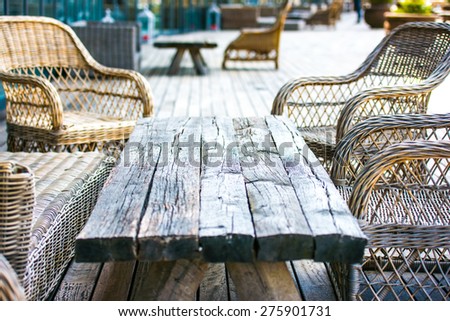 Rattan chairs and empty wooden table on terrace
