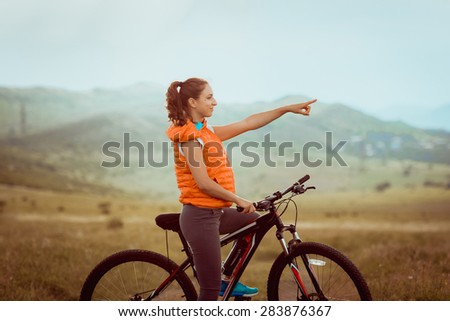 Beautiful girl riding on bicycle outdor on the rural road. Wellness and sport concept. Toned image
