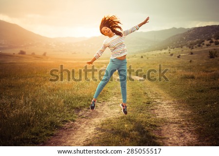 Beautiful girl jumping on the rural road. Happiness and freedom concept