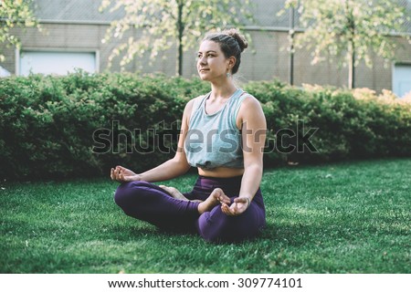 Yoga meditation in lotus pose in park.  Young woman in peace, soul and mind zen balance concept. Toned picture