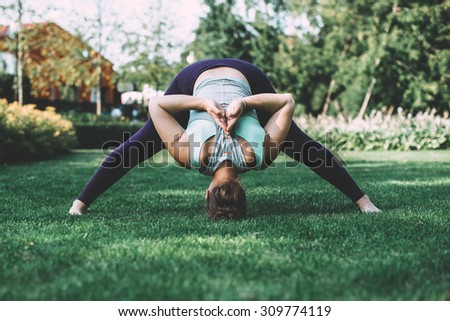 Young woman doing yoga exercise forward bend with hands in back Namaste gesture. Toned picture