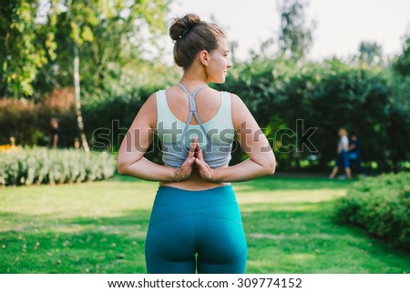 Young woman stands in back namaste yoga pose. Freedom concept. Calmness and relax, woman happiness