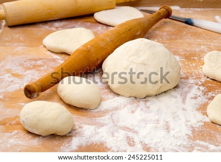 Cooking pies and cheesecakes at home. Dough and rolling pin on a working board.