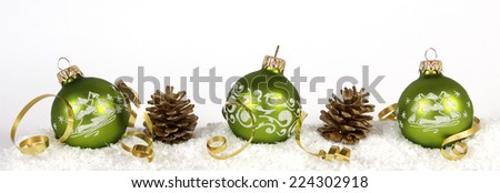 Green baubles and cones on the snow