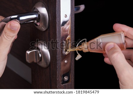 adjusting inner door lock using lubricating oil. indoors. fixing door squealed domestic problem. Foto d'archivio © 