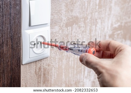 handyman repair wall outlet at apartment. worker using voltage electric tester to check outlet. electrician service concept. Photo stock © 