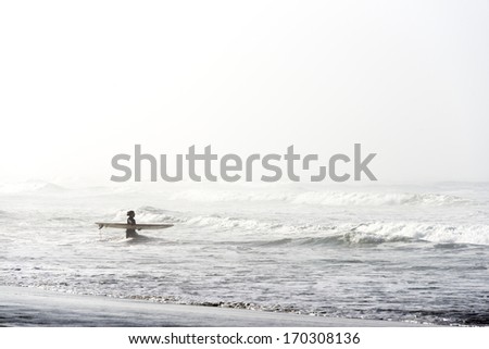 SAN FRANCISCO - OCTOBER 29: A late season surfer heads to the cold water with her board surrounded by the morning mist, in San Francisco, California, on October 29, 2012.