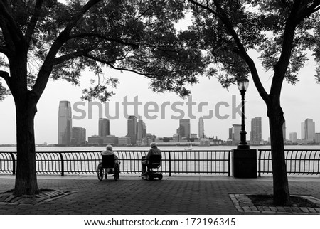 NEW YORK - JUNE 12: An old senior couple on wheelchairs enjoys the view of New Jersey\'s skyline from Battery Park on a pleasant June afternoon, on June 12, 2010 in New York.