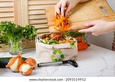 Sorted kitchen waste in paper eco bag on kitchen counter top. Compost-container. Sustainable life style. Woman throws vegetable and fruit peels, scrap from food preparation in trash-pack for recycling Foto stock © 