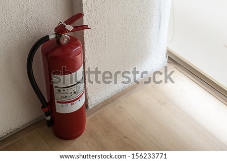 Fire extinguisher on wood floor in corner room