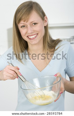 Beautiful woman in kitchen is making a cake