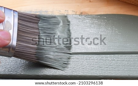A close up of the bristles of a wide decorator’s paint brush coated with green paint as it’s used to paint a wood surface  Stock foto © 