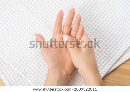 one female hand massages the other hand lying on a white towel with the open palm up. Closeup hand of person massage her hand from pain in healthy concept accupressure self-massage.