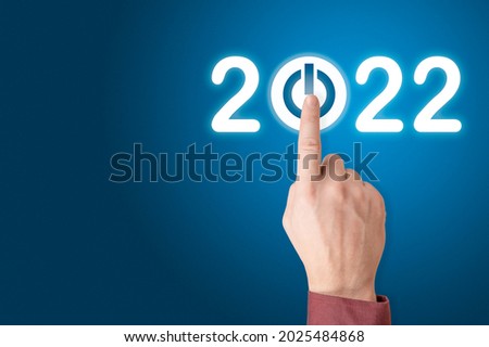 hand presses the start button for 2022. Happy New Year 2022. New Year New You, resolution, change, goal, vision, innovation and planning concept. Beginning of the New Year. copy space. blue background
