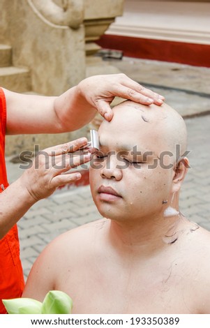 CHIANGRAI, THAILAND - APRIL 26   : Thai man gets his head shaved by a monk during a Buddhist ordination ceremony on April 26, 2014 in Chiangrai, Thailand.