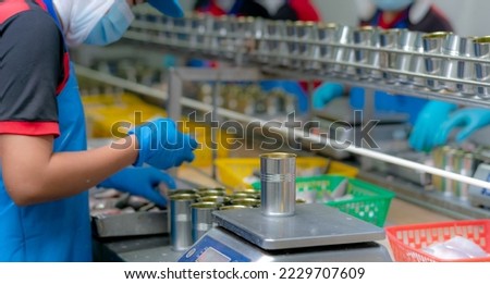 Worker working in canned food factory. Food industry. Canned fish factory. Workers weighing sardines in cans on a weight scale. Worker in food processing production line. Food manufacturing industry. Foto d'archivio © 